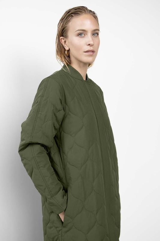 A shell coat featuring quilted lightweight padded matte fabric. Designed with a regular fit, round neckline, elasticated rib collar, side seam pockets, and concealed zip front closure.