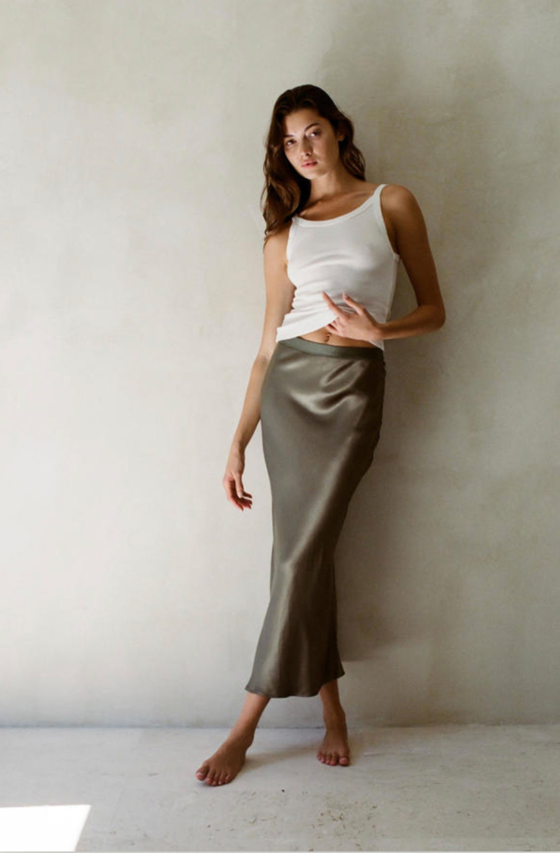 An olive satin skirt with a flowy fit, falling below the knee.