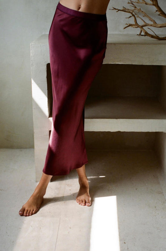 Maroon satin skirt with a flowy fit, falling below the knee.