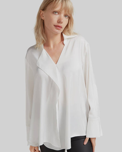 A white waterfall shirt with a cascading ruffle at the front, with a relaxed fit and long sleeves. Crafted from 100% recycled polyester.