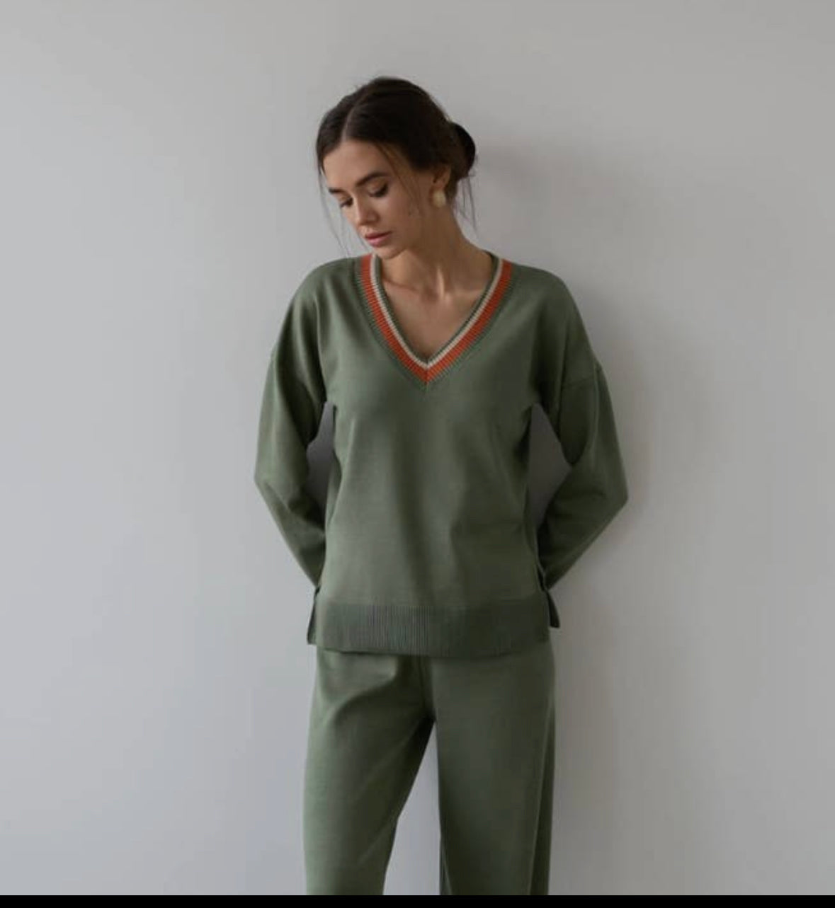 A cozy olive-colored V-neck sweater crafted with delicate cotton thread, accentuated by colorful cuffs. Its easy fit and flattering design make it a versatile addition to any wardrobe, ensuring both comfort and style.