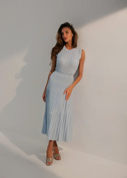 A feminine, soft, and airy dress in blue, designed to emphasize the body figure with a sleeveless, round neck style, falling below the knee.