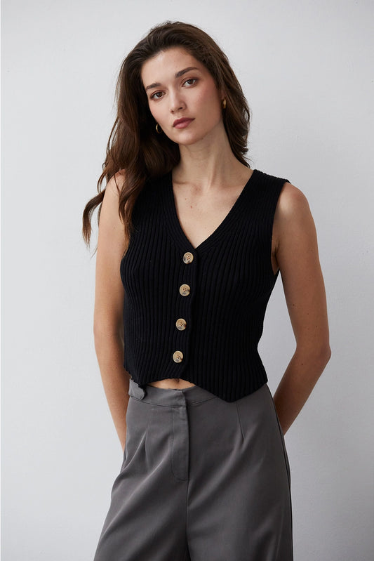 A sleeveless cotton sweater vest styled with a V-neckline and front button closure. The vest features a sweater rib knit and a V-shaped hem. Model is wearing size small.