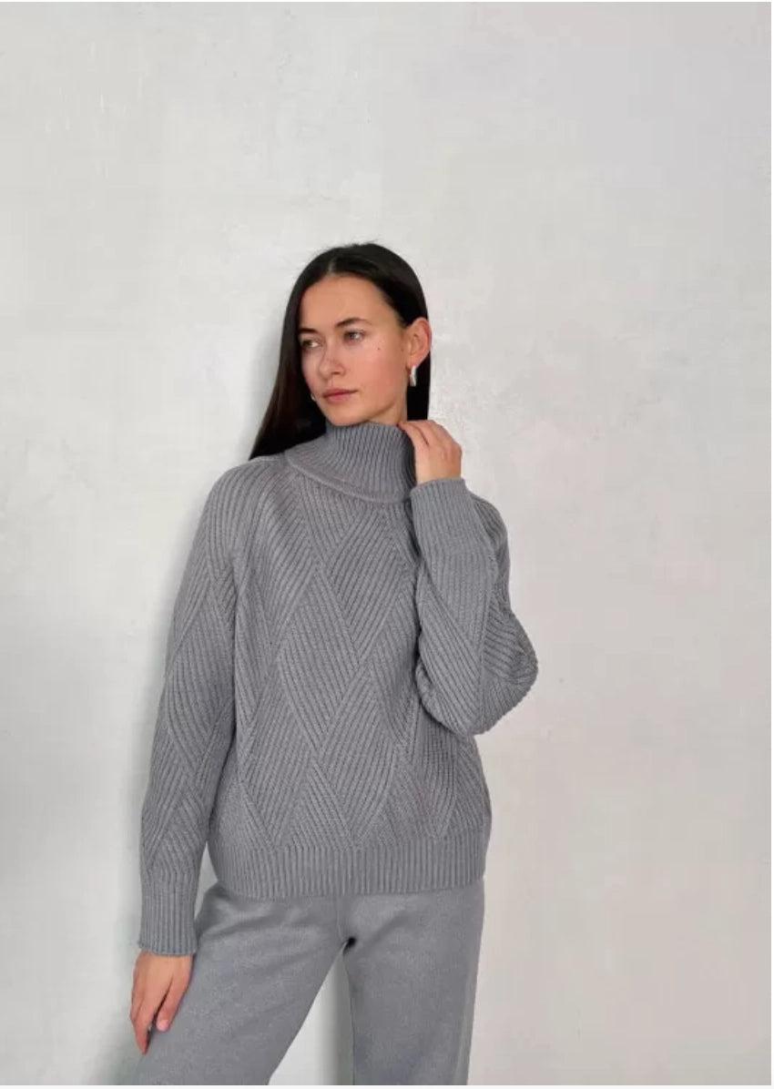 An oversized sweater crafted from gray cotton thread, featuring a relaxed fit with a high neckline and long sleeves. It has a ribbed finish and statement geometric print.