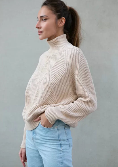 Oversized sweater made from cream cotton thread, with a relaxed fit, high neckline, and long sleeves. It boasts a ribbed finish and a statement geometric print.