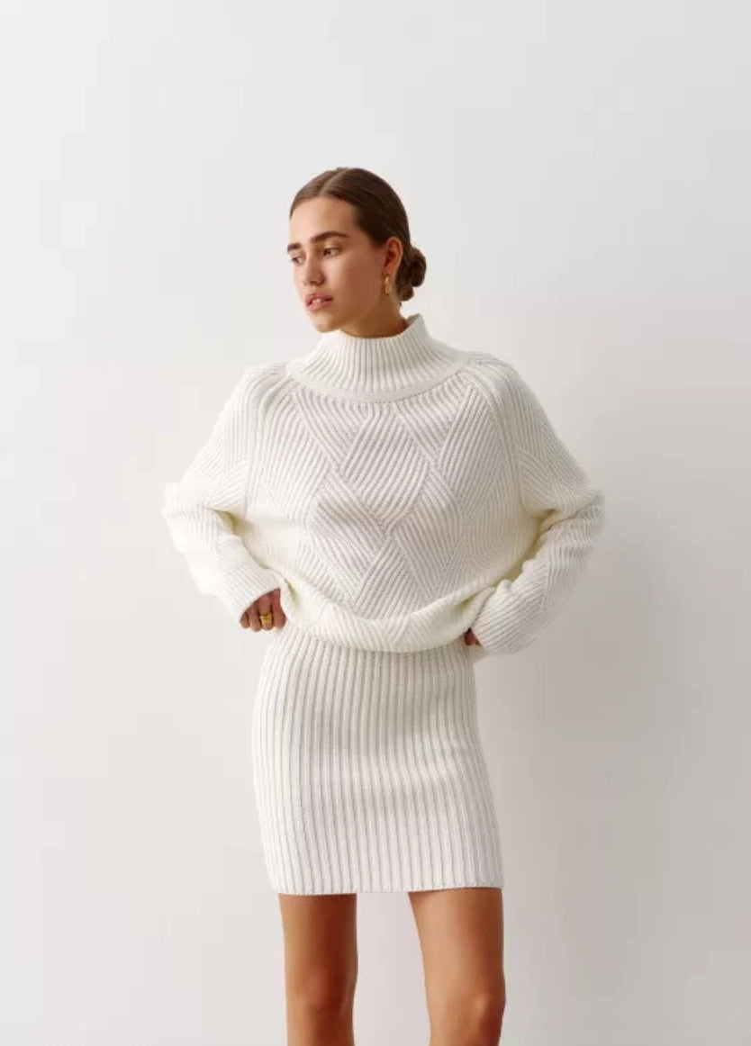 Oversized sweater crafted from milk-colored cotton thread, featuring a relaxed fit with a high neckline and long sleeves. It has a ribbed finish and a statement geometric print.